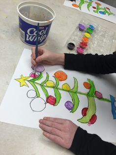 a child's hand holding a paintbrush and drawing on paper with crayons