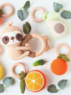 crocheted stuffed slotty toy surrounded by fruits and vegetables on white surface with green leaves