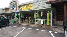 a car is parked in front of a store with surfboards on display and other items