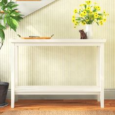 a white console table with yellow flowers on top and a potted plant next to it