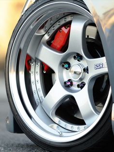 the front wheel of a silver car with red brake pads