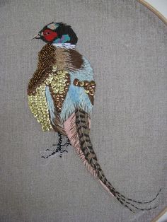 a colorful bird sitting on top of a piece of fabric next to a wooden frame