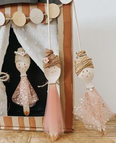 two wooden dolls in front of a photo frame with string and burlap decorations