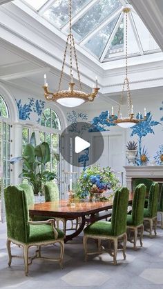 an elegant dining room with blue and white wallpaper, green chairs and a wooden table surrounded by potted plants