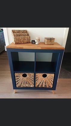 a blue cabinet with two baskets on top and a wicker basket in the bottom