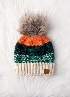 an orange, green and white knit hat with a pom - pom on top