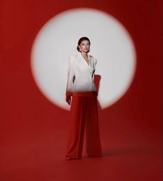 a woman standing in front of a red and white background with an object behind her