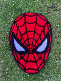 a close up of a spiderman face on the ground with grass in the background