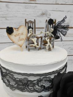 a white cake decorated with black lace and skeleton figurines sitting on top of it