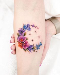 a woman's arm with flowers and stars on it