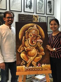 a man and woman standing next to an elephant painting on a easel in front of some pictures