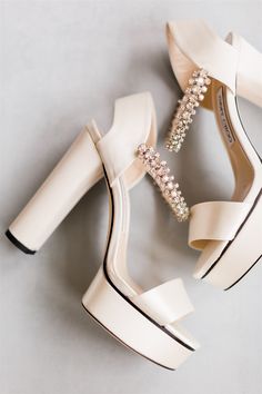 a pair of white high heeled shoes with crystal embellishments on them