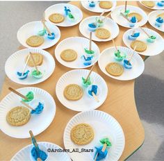 a table topped with paper plates filled with cookies and marshmallows on sticks