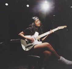 a woman sitting on top of a chair holding a guitar