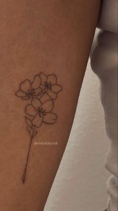 a woman's arm with a small flower tattoo on the left side of her leg