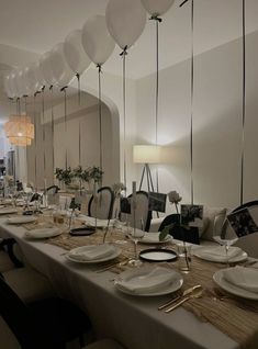 a long table is set with white plates and silverware for an elegant dinner party