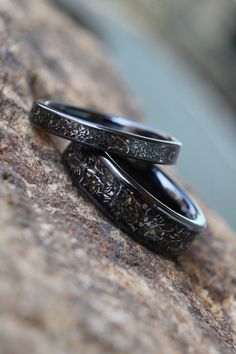 two wedding rings sitting on top of a rock