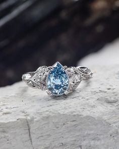 a blue diamond ring sitting on top of a rock