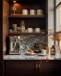 a marble counter top in a kitchen with coffee mugs and other items on it