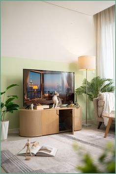 a cat sitting on top of a wooden entertainment center in front of a large window