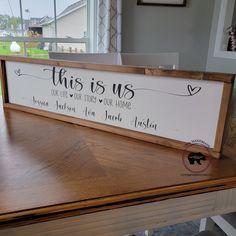 this is us sign sitting on top of a wooden table in front of a window