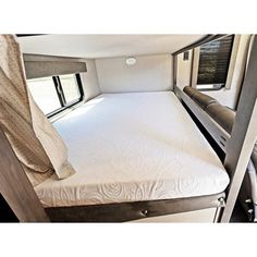 the inside of a camper with mattresses and windows