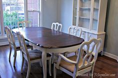 a dinning room table with chairs in front of a large window and bookcase