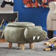 a toy crocodile footstool sitting on top of a carpeted floor next to a teddy bear