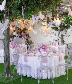 the table is set with pink and purple flowers, butterflies, and chandeliers