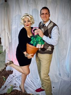 a man and woman pose for a photo with a fake plant in front of them