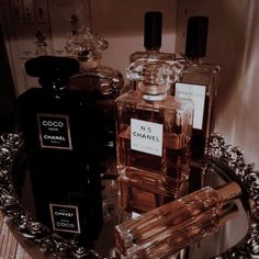 three bottles of perfume sitting on top of a glass plate in front of a mirror