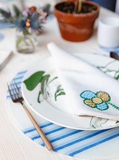 a white plate topped with a green flower next to a fork and knife on top of a table