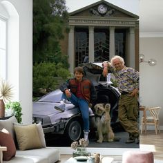 two people and a dog sitting in front of a car