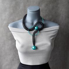 a mannequin wearing a black and white top with a turquoise beaded necklace