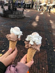 two people holding ice cream cones in their hands