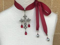 Cross necklace with red drop facetted glass crystals on grosgrain tie ribbon. Can be worn in many ways, as choker or as pendant, depending on you you tie the ribbon. The cross is antique silver in zinc alloy, has facetted glass stones. The neck band dark red grosgrain 2.5cm or 1 inch width. Red facetted tear drop glass. Measurements are as follows: Cross height is 8cm Cross width is 5.5cm Total length of pendant including bail and red drop crystal is just under 12cm I can customise the necklace Elegant Cross Choker As A Gift, Elegant Silver Cross Choker, Goth Victorian, Cross Choker Necklace, Layered Pearl Necklace, Cross Choker, Tie Ribbon, Large Pendant Necklace, Mens Leather Sandals