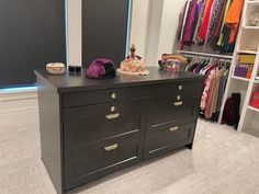 a black dresser in a closet with clothes on it