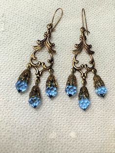 "Victorian Style Blue Facetted teardrop Crystal Earrings                                                                                                                                        ~                                     Three fabulous blue facetted crystals suspended from a bronze colour Victorian style component.                                                                              The earrings measure 2 1/2\" long and are in excellent condition. Blue Teardrop Metal Chandelier Earrings, Blue Metal Teardrop Chandelier Earrings, Vintage Blue Dangle Chandelier Earrings, Blue Vintage Dangle Chandelier Earrings, Blue Teardrop Brass Earrings, Victorian Gold Earrings, Victorian Style Earrings, Teardrop Earrings Gold, Bronze Colour