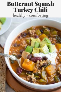 a bowl of butternut squash turkey chili with bread and avocado on the side