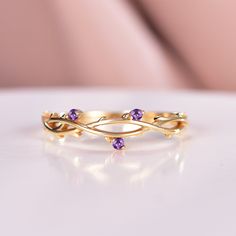 a gold ring with two amethysts on it sitting on a white surface