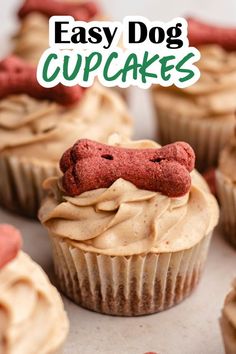 cupcakes with frosting and dog head on top are shown in the foreground