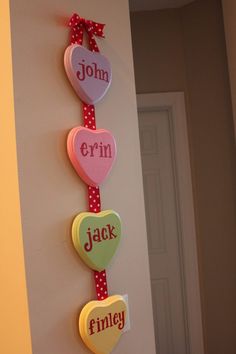 a wall hanging on the side of a door that has hearts and name signs attached to it