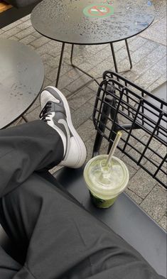 a person's feet resting on a table with a drink in front of them