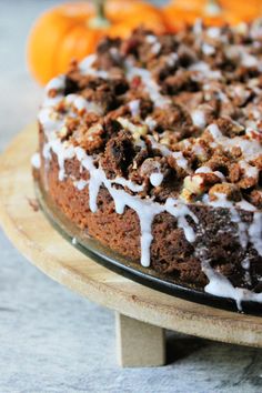 a cake sitting on top of a wooden platter next to oranges in the background