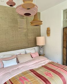 a large bed sitting in a bedroom next to a tall wooden headboard with lights hanging from it