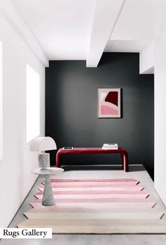 a room with black walls and pink rugs on the floor in front of a painting