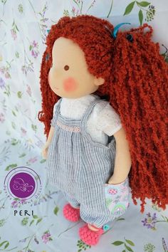 a doll with long red hair is sitting on a floral background and has the words peri written above it