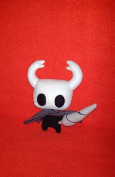 a white stuffed animal with horns on it's head sitting in front of a red background