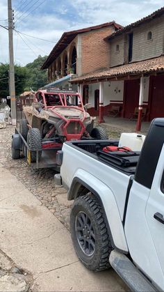 a white truck pulling a trailer down a street next to a red brick building with two cars on it