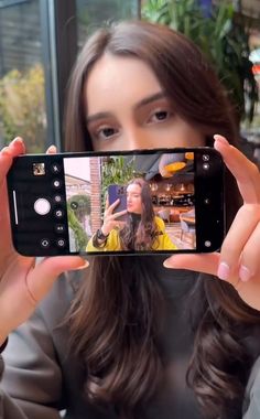 a woman is taking a selfie with her cell phone in front of her face